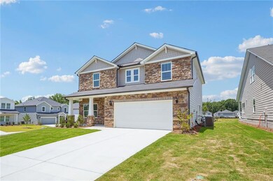 Craftsman-style house with stone siding, a front lawn, an attached garage, and driveway