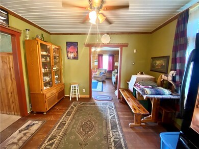 Dining area open to kitchen with original wood floors and ceiling fan.