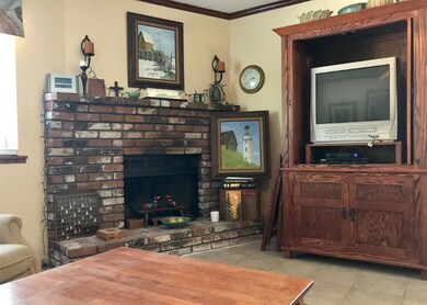 Living room includes a brick fireplace. (stained g