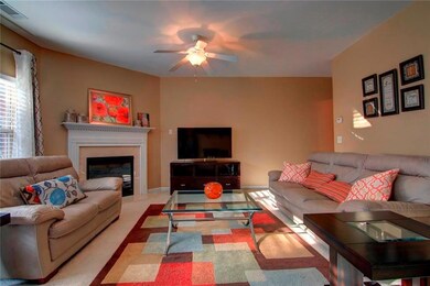 Carpeted living area with a ceiling fan and a glas