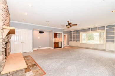 An alternative view of this great room reveals the French door entry from the foyer, mammoth bay window + wall-to-wall CUSTOM built-in shelves and cabinetry. The great room also includes a media niche, closet for storage, and a wet bar with sink + beverage refrigerator.