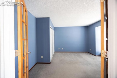 Carpeted spare room with baseboards, a textured ceiling, and french doors
