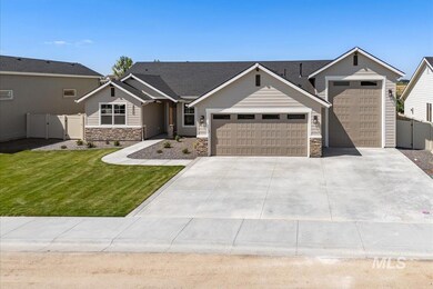 View of front facade featuring stone siding, an attached garage, driveway, and a gate