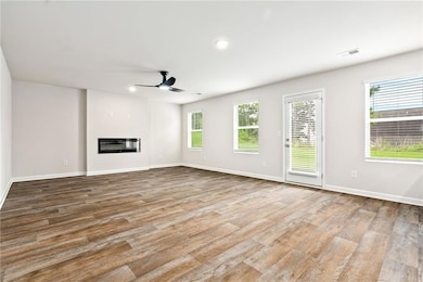 Unfurnished living room with a glass covered fireplace, light wood finished floors, recessed lighting, and a ceiling fan