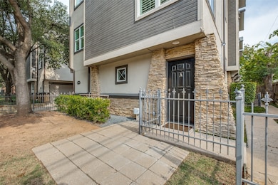 Property entrance with stone siding, a gate, stucco siding, and a patio area