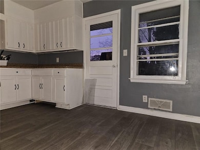 Kitchen featuring visible vents, white cabinets, b
