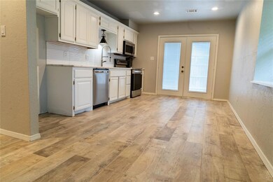 Kitchen featuring granite countertops appliances with stainless steel finishes, french doors, light countertops, light wood-type flooring, and recessed lighting