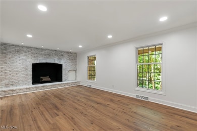 Unfurnished living room featuring hardwood / wood-style floors, ornamental molding, recessed lighting, and a fireplace