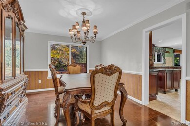 Dining space with wainscoting, crown molding, wooden walls, light wood finished floors, and a chandelier