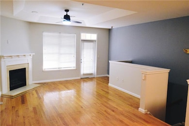 living room featuring a tray ceiling, a ceiling fan, a fireplace, and wood finished floors