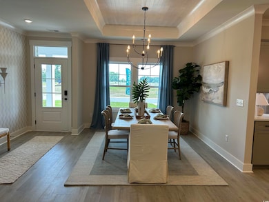 Dining area featuring light wood-style flooring, a tray ceiling, crown molding, and a chandelier