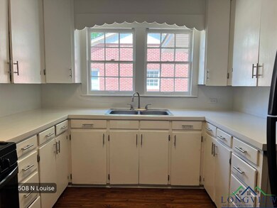 Kitchen with a sink, white cabinets, light countertops, and stove