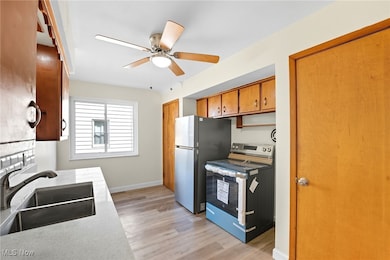 Kitchen featuring appliances with stainless steel finishes, brown cabinets, light wood finished floors, and ceiling fan