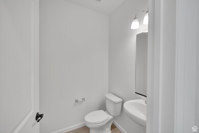 Bathroom with wood finished floors, toilet, a sink, and baseboards