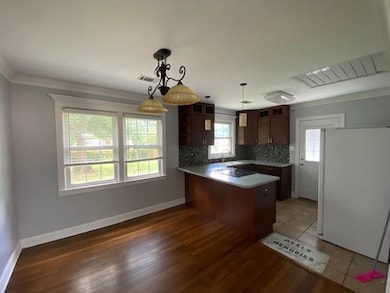 Kitchen featuring freestanding refrigerator, backsplash, a peninsula, decorative light fixtures, and ornamental molding