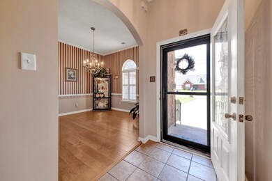 Entryway with a chandelier, arched walkways, baseboards, crown molding, security doors and light wood finished floors