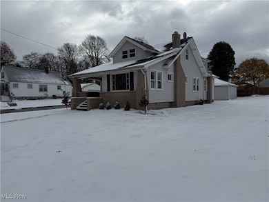 Bungalow with brick siding, a porch, a chimney, and an outdoor structure