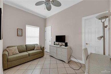 Living room featuring ceiling fan, light tile patterned floors, and ornamental molding