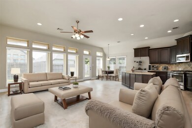 This expansive living room seamlessly flows into the modern island kitchen, creating an open and airy space perfect for entertaining. The large windows flood the room with natural light, highlighting the sleek ceramic tile flooring and high ceilings.