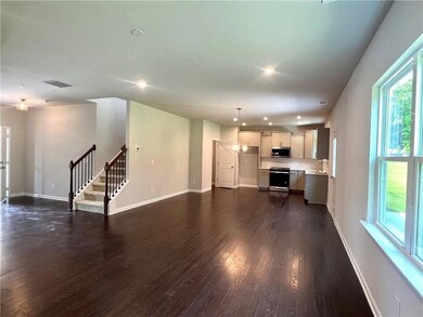Unfurnished living room featuring dark wood-style floors, recessed lighting, and stairway