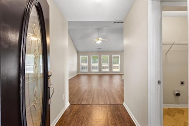 Corridor featuring wood finished floors, vaulted ceiling, and a textured ceiling