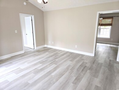 Empty room featuring ceiling fan, baseboards, vaulted ceiling, and light wood-type flooring