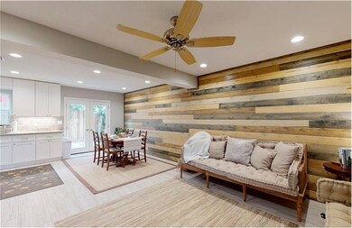 Living area with ceiling fan, wood accent wall, be