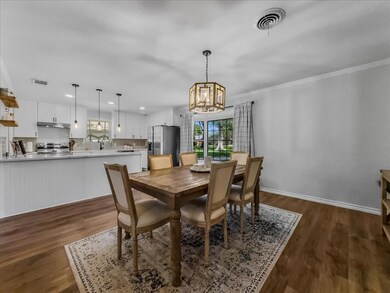 Dining area with LVP floors, a chandelier, bay window and ornamental molding