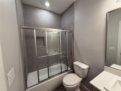 Full bathroom with shower / bath combination with glass door, vanity, and toilet