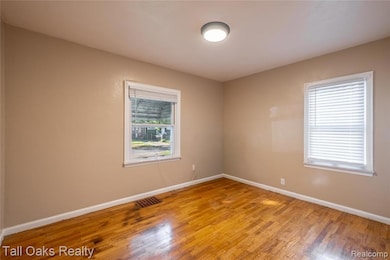 Spare room with baseboards and wood-type flooring