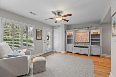 Living room with ceiling fan and light hardwood / 