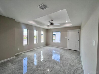 Spare room with baseboards, a ceiling fan, visible vents, a raised ceiling, and marble finish floor