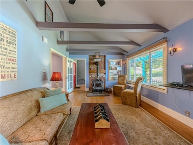 Living room with a wood stove, wood finished floors, and french doors
