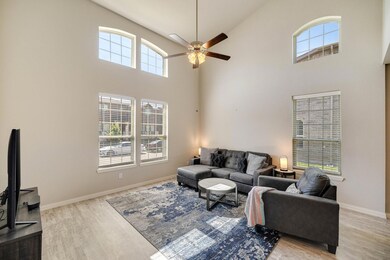Living room with high vaulted ceiling, plenty of natural light, light wood-type flooring, and ceiling fan
