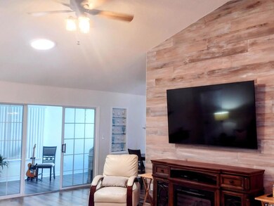 Living room featuring ceiling fan, wood finished floors, and high vaulted ceiling
