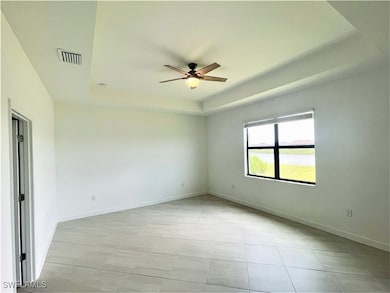Spare room featuring a tray ceiling, a ceiling fan