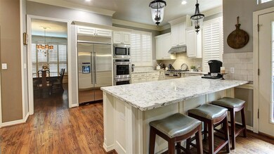 View of formal dining room from Kitchen. Additional seating with the gorgeous quartz counter tops. Built in refrigerator, double ovens and microwave. Top of the line gas cooktop. This kitchen is a chef's dream. The stools convey with the house.