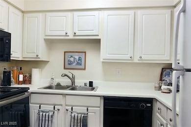 Kitchen with light countertops, black appliances, and white cabinets