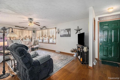 Living room with a textured ceiling, wood finished floors, and ceiling fan