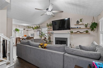 Living area featuring a fireplace, dark wood-type flooring, a textured ceiling, stairs, and lofted ceiling