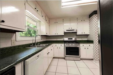 Kitchen with stainless steel gas stove, dishwasher, a sink, under cabinet range hood, and light tile patterned floors