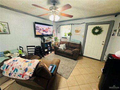 Tiled living room featuring ceiling fan, a textured ceiling, and crown molding