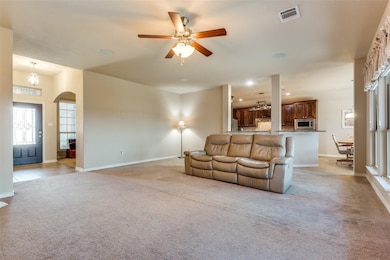 Living room featuring light colored carpet, a ceiling fan, recessed lighting, and arched walkways