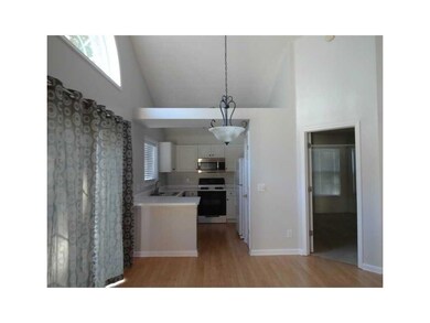 Kitchen featuring stove, stainless steel microwave, white cabinets, a sink, and light countertops