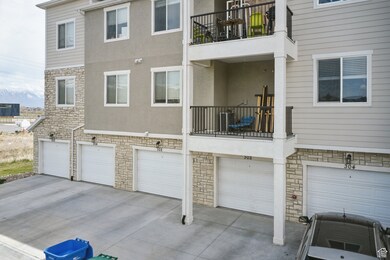 Back of house featuring stone siding, a balcony, an attached garage, and stucco siding