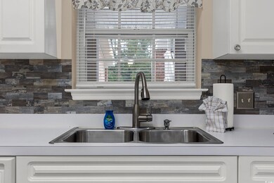 Kitchen with white cabinetry, backsplash, and sink