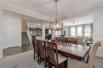 Carpeted dining space featuring stairs, baseboards, ornamental molding, and an inviting chandelier