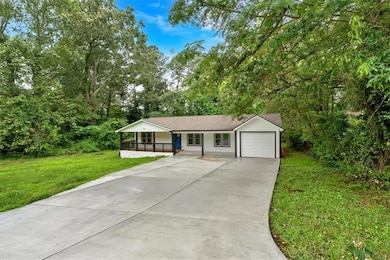 Single story home featuring a front yard, concrete driveway, a garage, and a porch
