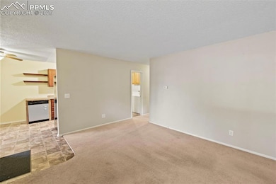 Unfurnished living room featuring a textured ceiling, a ceiling fan, and light carpet