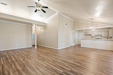 Living room with a fireplace, vaulted ceiling, crown molding, and laminate flooring